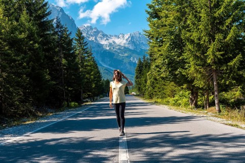 Young tourist walking on the road in Valbona valley, Theth national park, Albanian Alps, Valbona