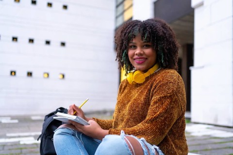 Portrait of black ethnic girl sitting in college doing classwork or studying for an exam on back to