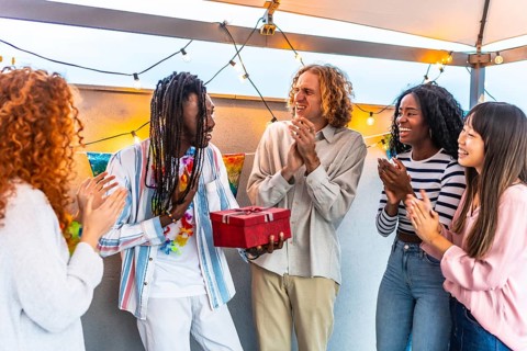 African man thanking his multi-ethnic friends for the birthday gift they gave him during a party on