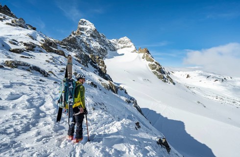 Mountaineer with skis at the fork Porta d'Es-cha, view of mountain peak Piz Kesch and glacier