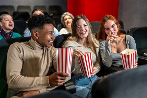 Young people enjoying a movie at the cinema, sharing laughter and popcorn, creating memorable