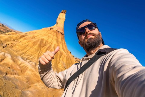 Tourist making thumbs up sign enjoying the view of the geological formations in bardenas reales