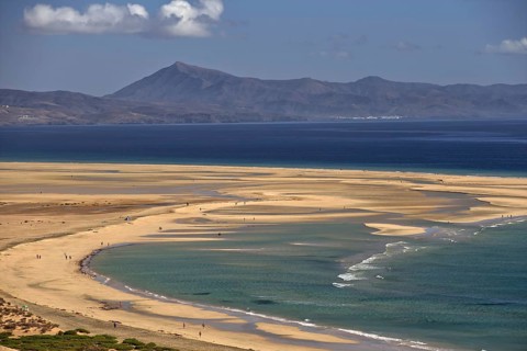 Endless beach Playa Risco del Paso, Playa de Sotavento with gentle waves, surrounded by mountains,
