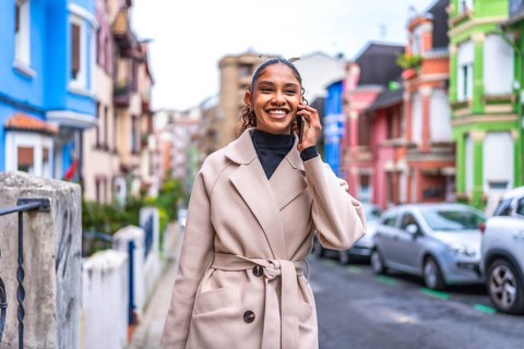 Smiling african businesswoman talking to the mobile phone walking along a colorful street in the