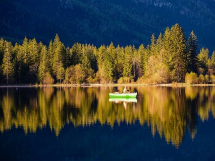 Angler in a rowing boat on the Hintersee in the first sunlight, Berchtesgaden National Park,