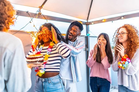 Multiracial young group of friends at terrace covering the eyes of a woman to surprise her with