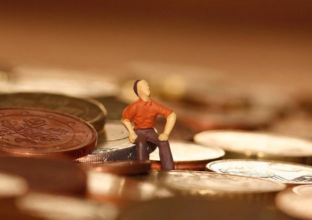 Miniature man sitting among euro coins, North Rhine-Westphalia, Germany, Europe