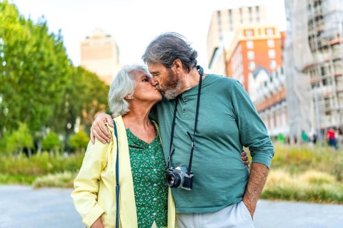 Frontal portrait of a senior couple kissing while visiting a city