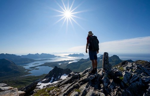 View of mountains and fjord landscape, mountaineer at the summit of Rundfjellet, Sun Star,