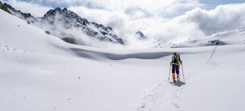 Atmospheric clouds in a wintry mountain landscape, ski tourer on the ascent to Porta d'Es-cha,