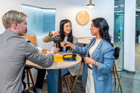 Businesswomen and businessmen enjoying a coffee break in a modern coworking office, fostering