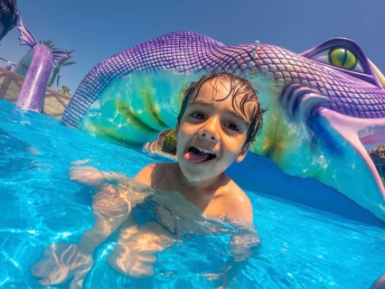 Happy child sticking out his tongue, enjoying playful moments at a vibrant water park during a