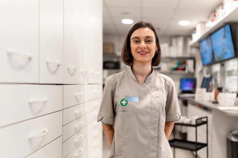 Young and proud female pharmacist standing with arms in the back in the storage room in a modern