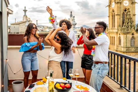 Excited multi-ethnic friends dancing during rooftop evening party in the city