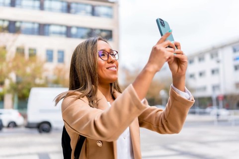 Latin female traveler taking photos of a city while walking along the street