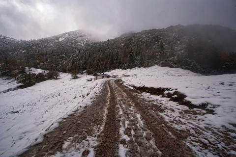 Snowy mountain landscape with cloudy sky and a narrow hiking trail to the Herzogstand, Kochel am