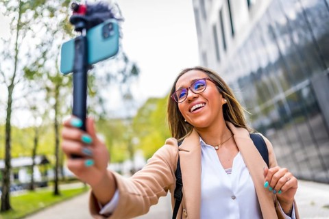 Latin woman vlogger talking to the camera while recording video blog in the city