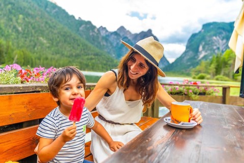 Mother and son enjoying a lakeside snack with a picturesque mountain backdrop in the dolomites