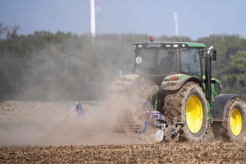A tractor works a field, due to long dryness in spring, no rain for more than 4 weeks, the fields