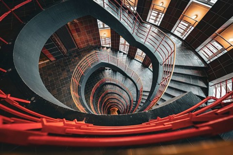 Dramatic spiral staircase with an open-height barrel and red railings, SPRINKENHOF, Hamburg,