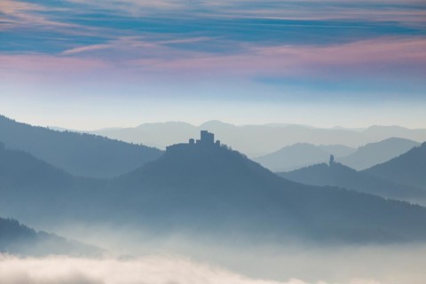Autumnal panorama of the Palatinate Forest with mountain peaks and valleys in the mist. Trifels