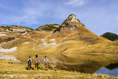 Three men play the alphorn at Lake Augstsee on Mount Loser. The Austrian alphorn trio Klangholz.