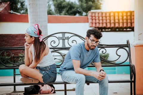 Unhappy couple sitting back to back on bench. Concept of couple problems and crisis. Upset young