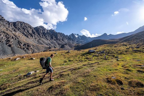 Mountaineers on a hiking trail, green high valley in atmospheric light, Keldike Valley on the way