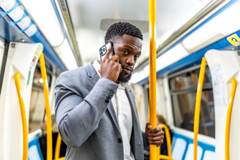 Young businessman commuting on public transport, using smartphone to stay connected while
