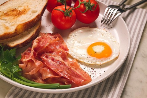 Frühstück, Spiegelei, Speck und Brot, mit Kirsche, auf einem hellen Hintergrund, hausgemacht, keine