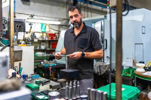 Male caucasian operator performing quality control on metal pieces in the factory using a