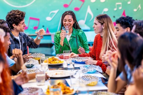 Young multiethnic friends enjoying meals and drinks together in a vintage restaurant, creating a