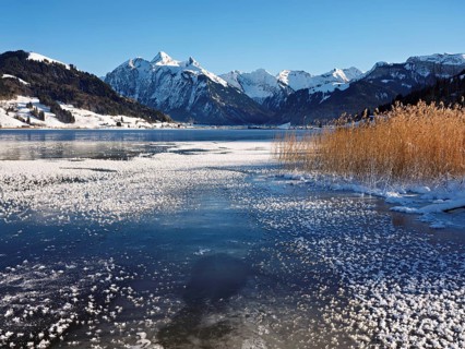 Frozen Sihlsee, reservoir, behind the snow-covered mountains Flübrig and Druesberg, Euthal, Canton