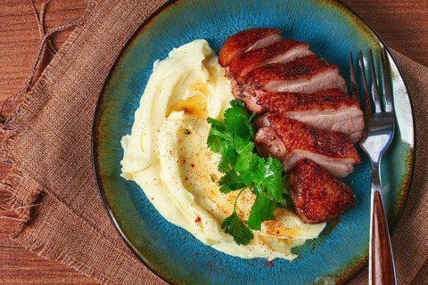 Roast duck breast, sliced with mashed potatoes, on a plate, close-up, no people