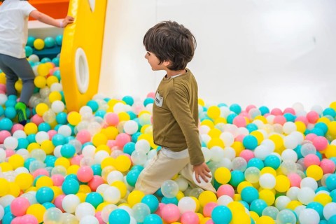 Young boy joyfully playing in a vibrant ball pit, surrounded by a colorful playground that sparks