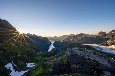 Picturesque mountain landscape at sunrise with sun star, fjord Trollfjord and Raftsund, hike to