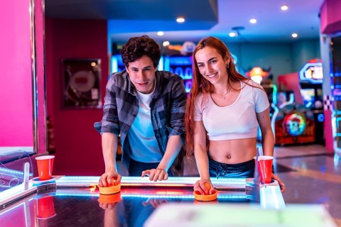 Multiethnic friends enjoying a weekend together, playing air hockey in a vibrant entertainment