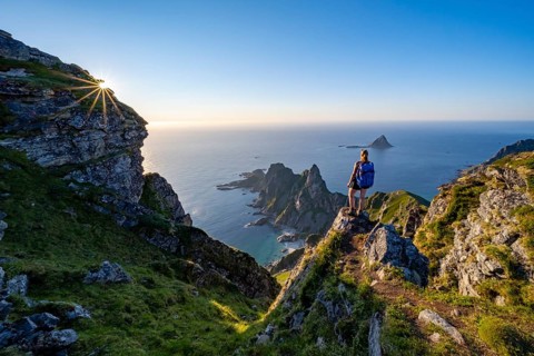 Mountaineer on the summit of Måtind or Måtinden, view of picturesque coastal landscape with sun