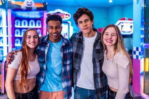 Four young multiethnic friends embrace, enjoying their weekend together at a vibrant bowling alley