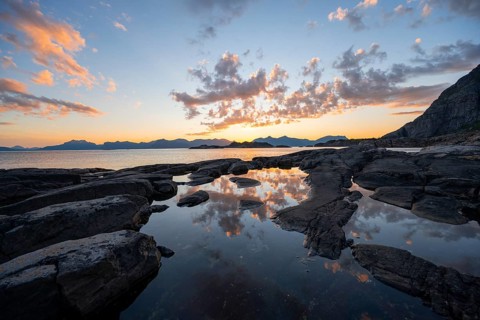 Clouds reflected in a small pond on a rocky coast, coastal landscape at sunset, Henningsvær,