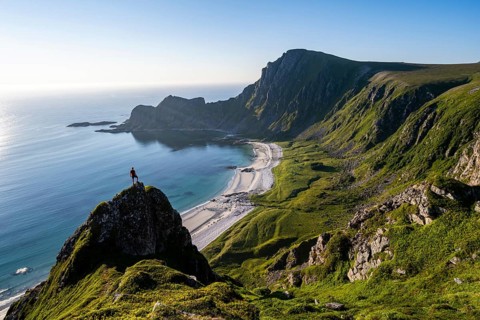 Climber on a rock, view of picturesque coastal landscape, steep coast with peak Måtind or Måtinden,