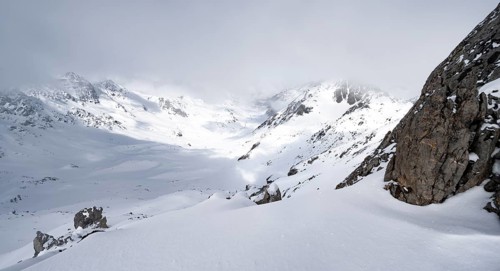 View of cloudy valley from the summit of Piz Laviner, mountain landscape in winter, Grisons Haute