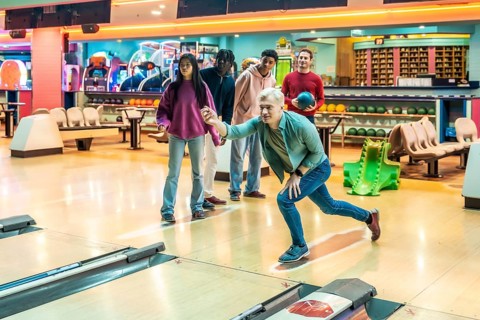 Diverse group of young adults having fun bowling together, enjoying a weekend leisure activity