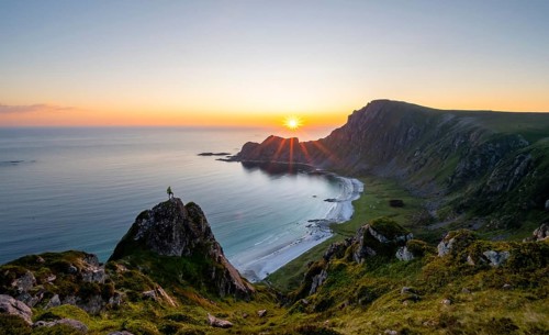 Climber on rocks in front of picturesque landscape, view of coastal landscape at sunset, cliffs and