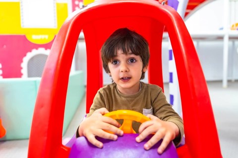 Preschooler having fun driving an imaginary car in kindergarten, engaging in playful learning and