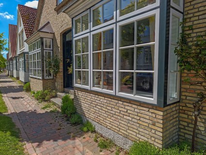 Historic row of houses with bay windows in Lange Strasse, gabled houses, footpath, trees, Arnis,