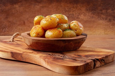 Baked new potatoes, with butter and dill, on a wooden plate, homely, rustic, no people