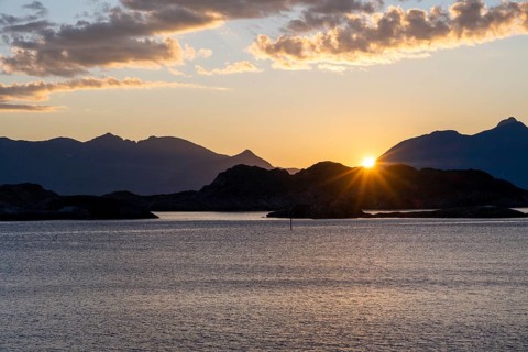 Sun setting behind Bergen, coastal landscape at sunset, Henningsvær, Lofoten, Nordland, Norway,
