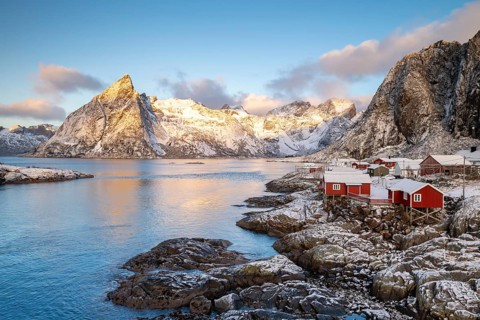 Rorbuer fishing huts in front of snow-covered mountains in winter, Hamnøy, Moskenesøy, Lofoten,