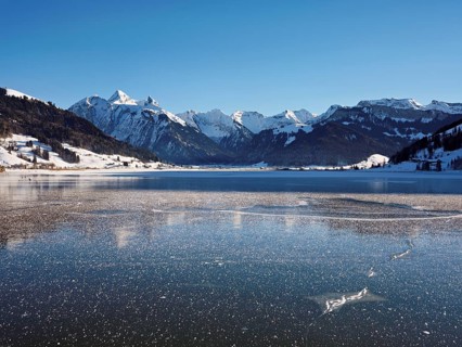 Frozen Sihlsee, reservoir, behind the snow-covered mountains Flübrig and Druesberg, Euthal, Canton